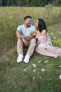 Couple sitting together in the grass looking at each other lovingly