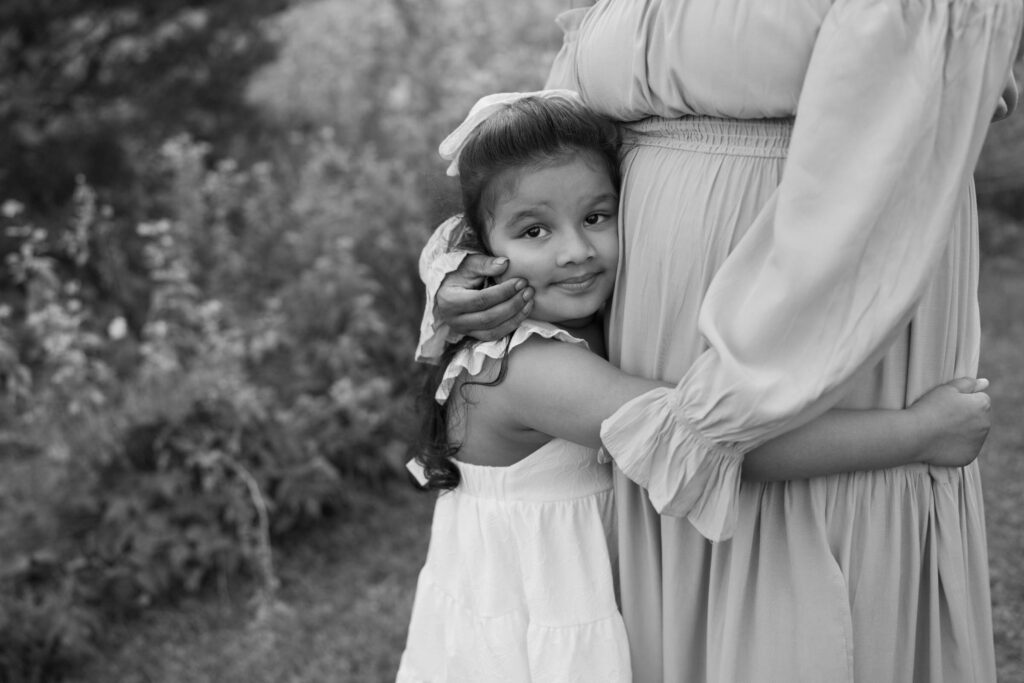 Girl wrapping arms around mother and mother holding her face with her hand