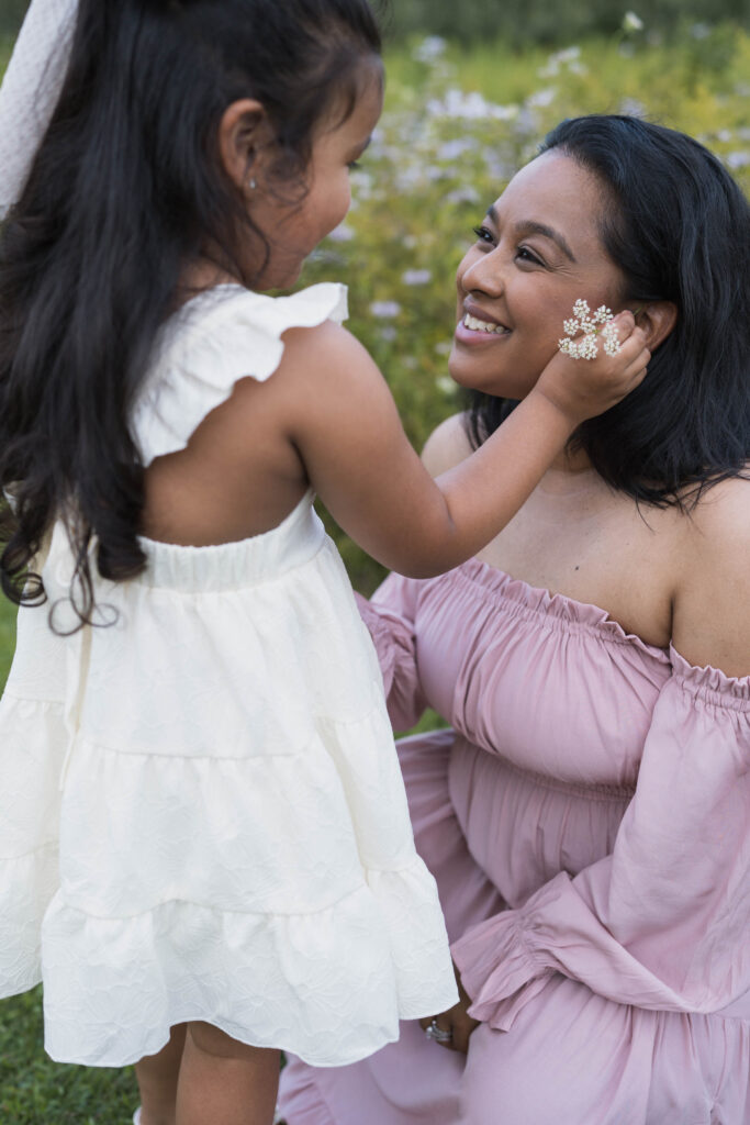 Little girl putting Queen Anne's Lace behind mother's ear