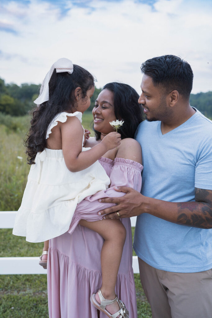 Family smiling at one another near white fence